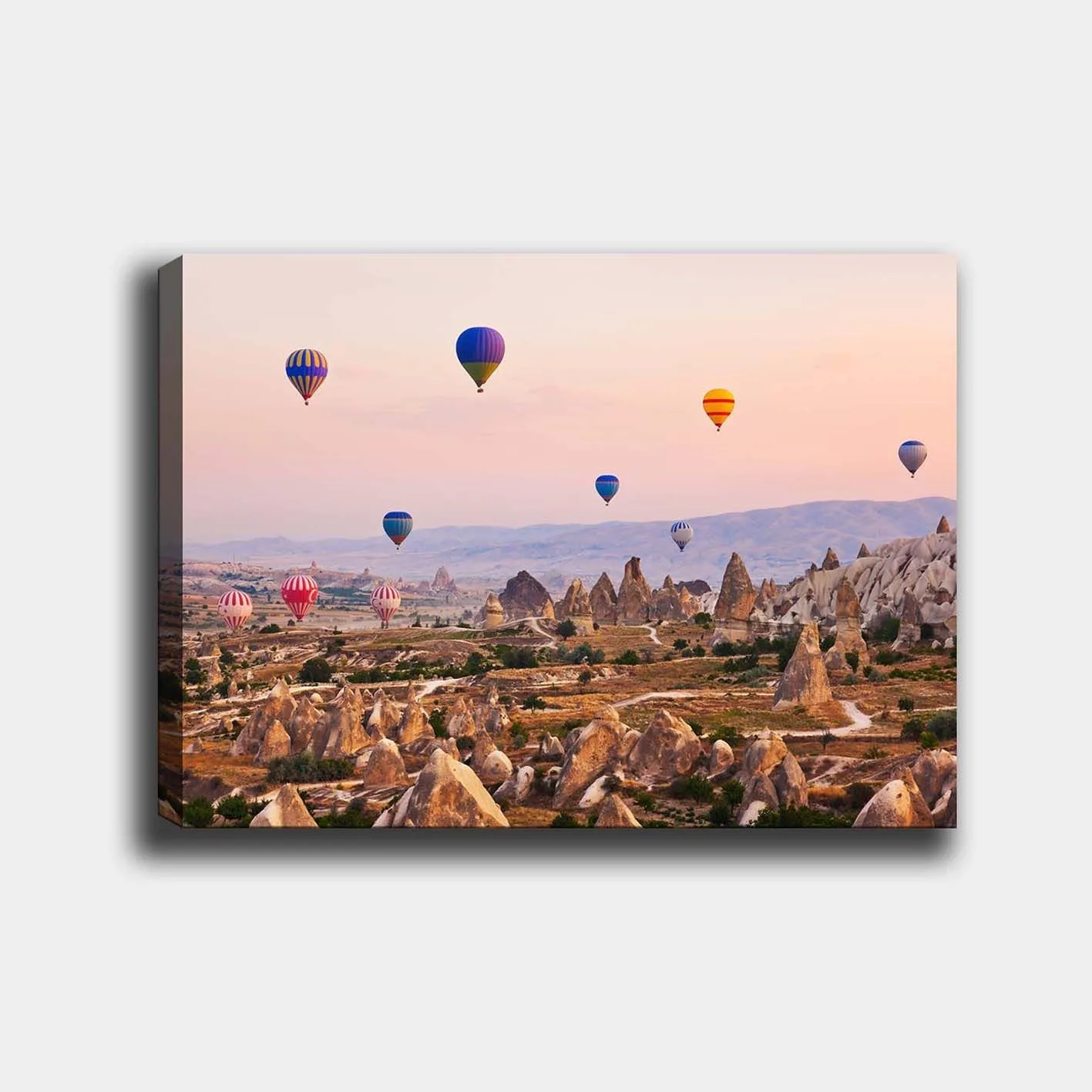 Canvastavla 70x100 cm - Flera färgglada luftballonger sväva över en dramatisk landskap med unika klippformationer - Blå / Röd / Orange