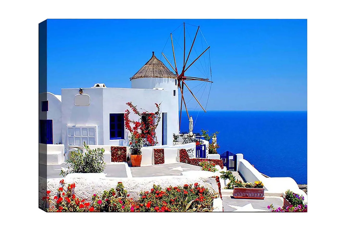 Canvastavla 70x100 cm - Pittoresk vy av en vitkalkad byggnad med en traditionell vindmölla och färgglada blommor i Santorini - Vit / Blå / Röd